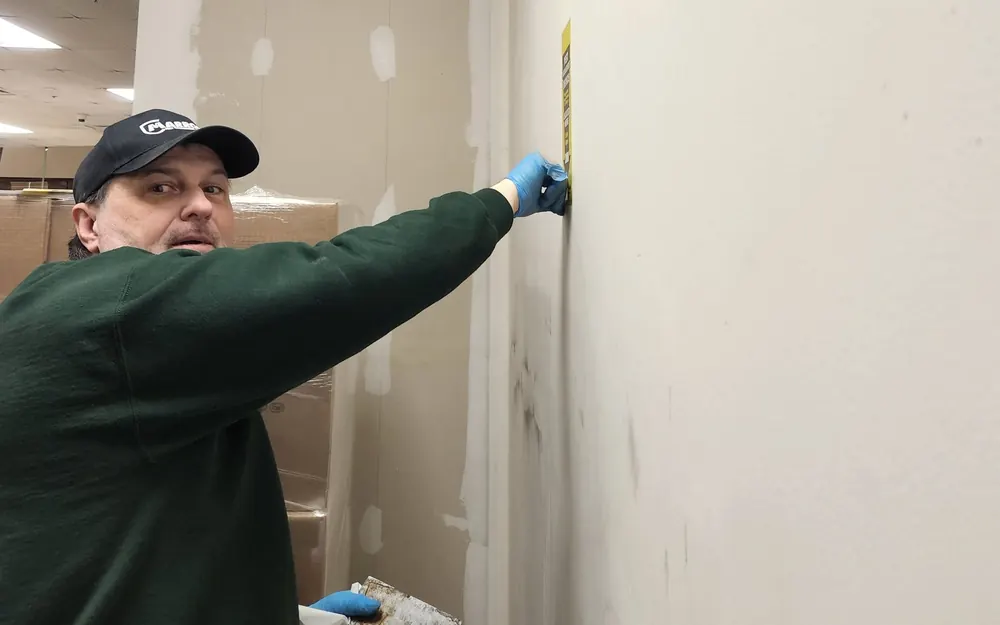 A Marrone technician in a company cap treating the base of an interior wall